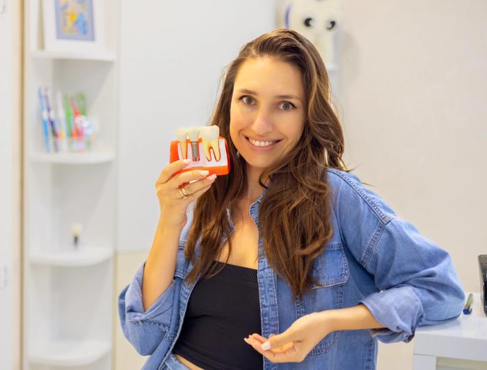 a woman is holding a model of her teeth and smiling .