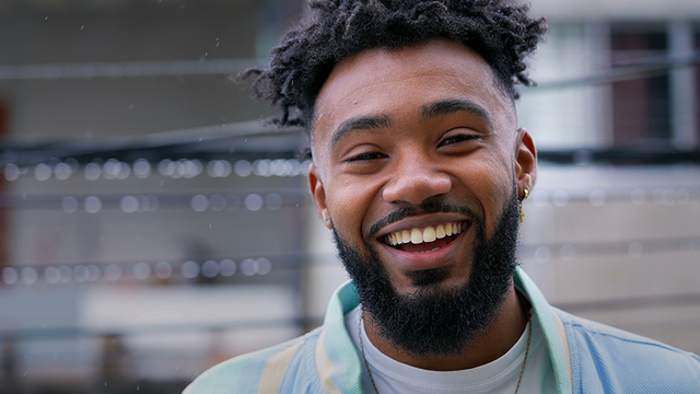 a man with a beard and earrings smiles for the camera