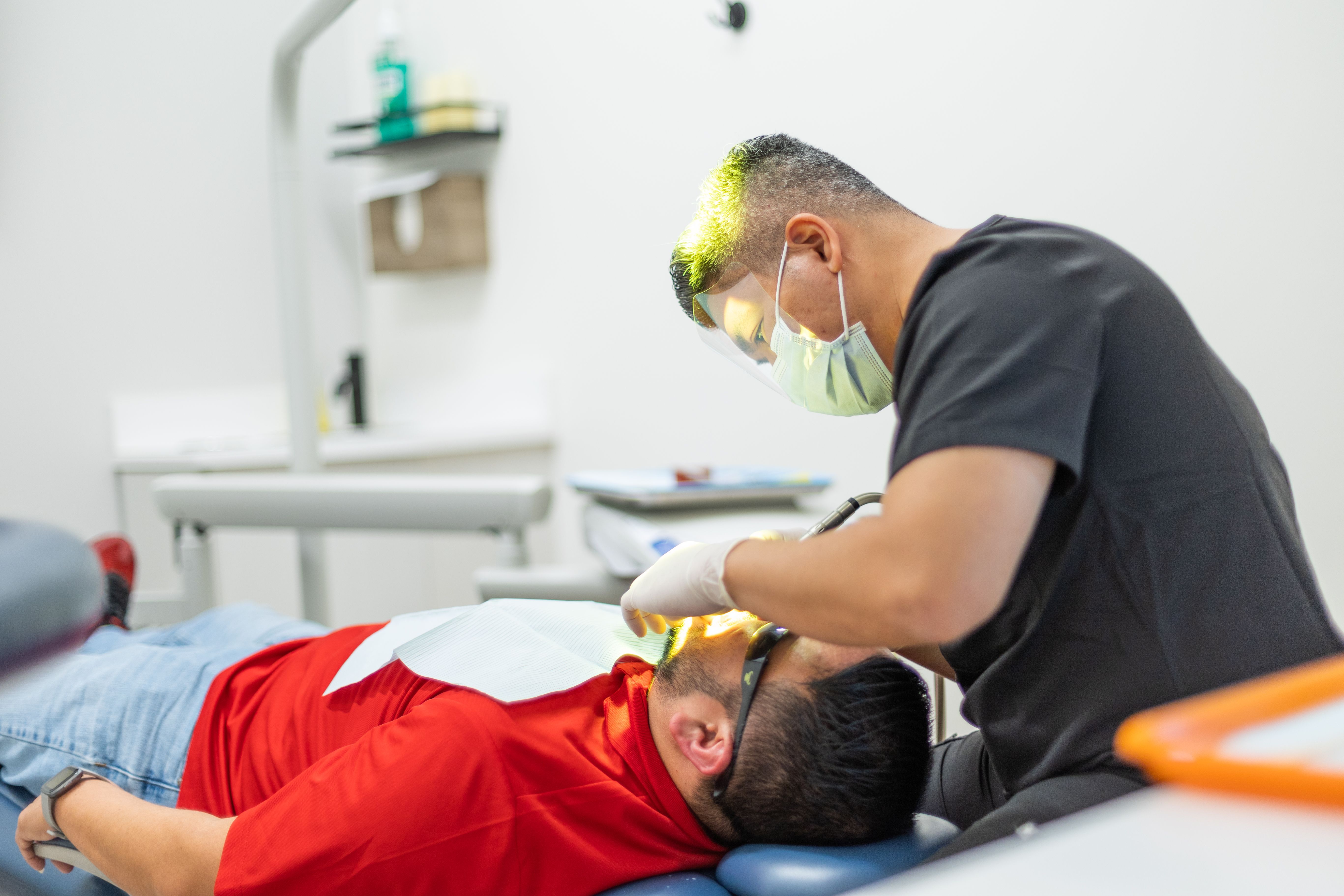 a man is getting his teeth examined by a dentist in a dental office .
