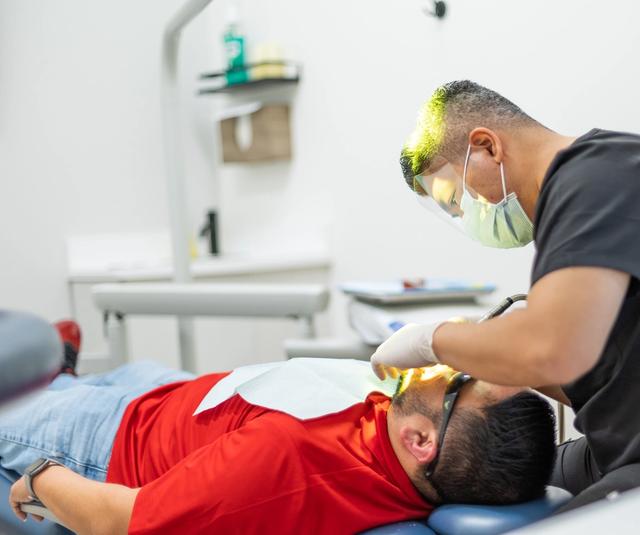 a man is getting his teeth examined by a dentist in a dental office .