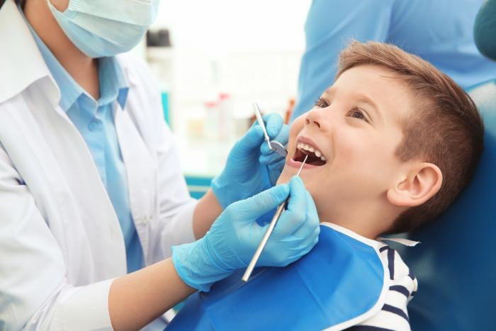 a young boy is getting his teeth examined by a dentist .