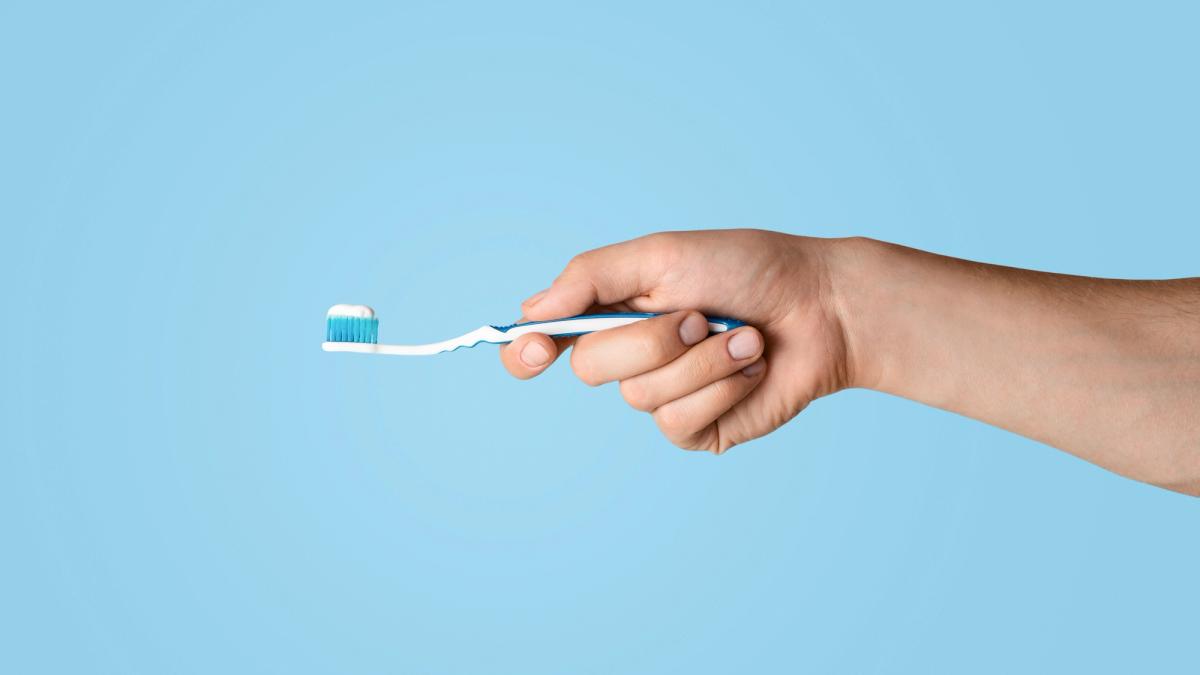 a person is holding a toothbrush with toothpaste on it .