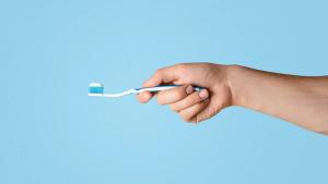 a person is holding a toothbrush with toothpaste on it .