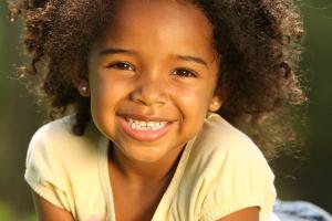 a little girl with braces on her teeth is smiling for the camera .