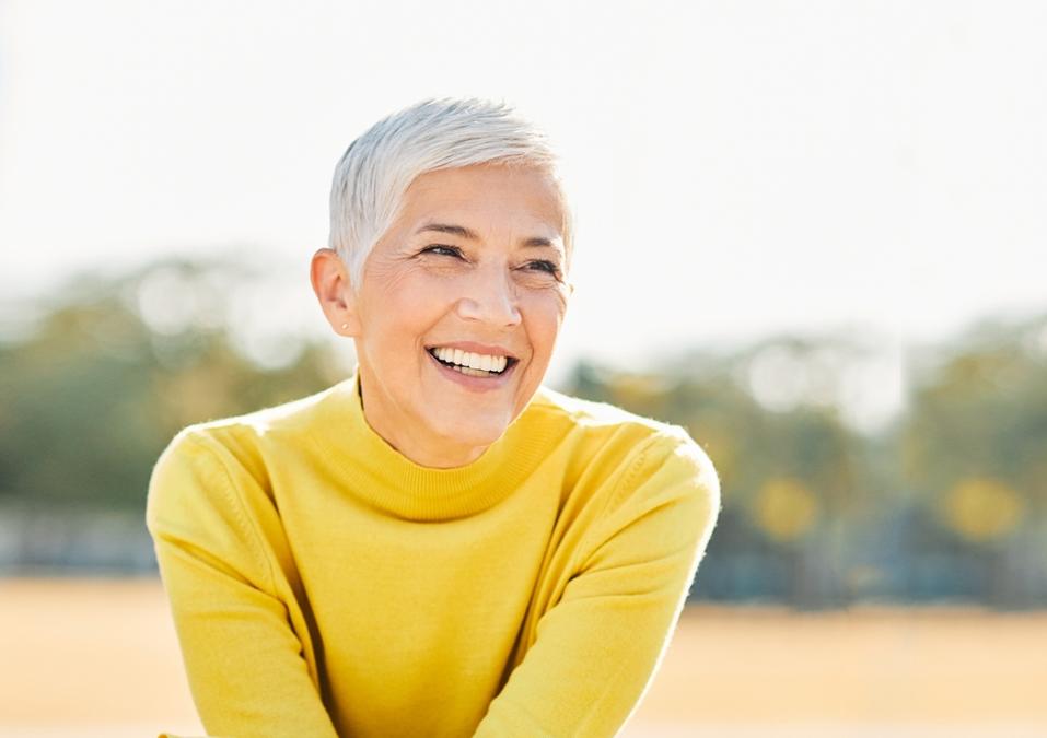 the woman is wearing a yellow sweater and smiling .