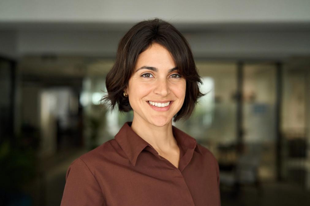 a woman in a brown shirt is smiling for the camera .