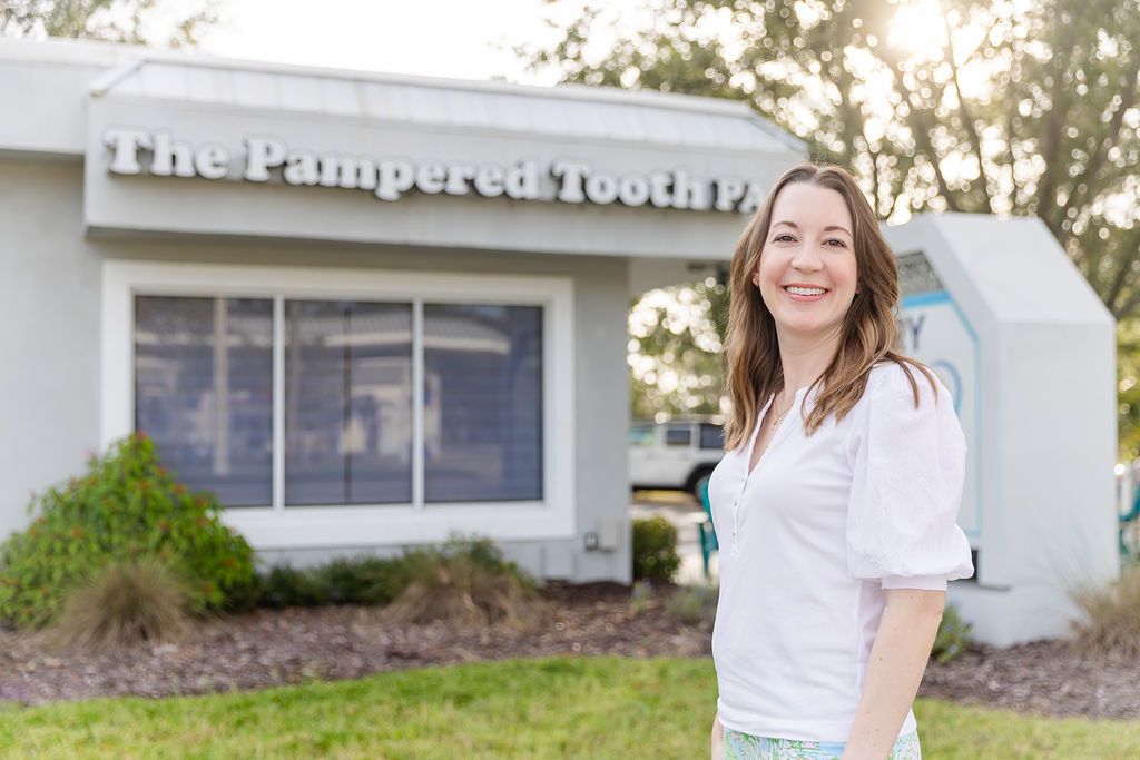 Smiling woman standing outside "The Pampered Tooth PA" building.