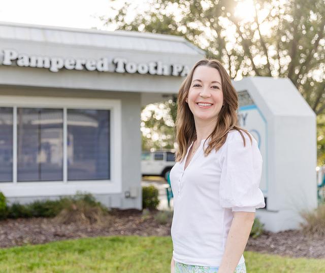 Smiling woman standing outside "The Pampered Tooth PA" building.