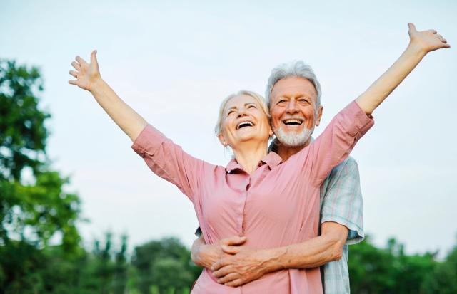 an elderly couple is standing next to each other with their arms outstretched .