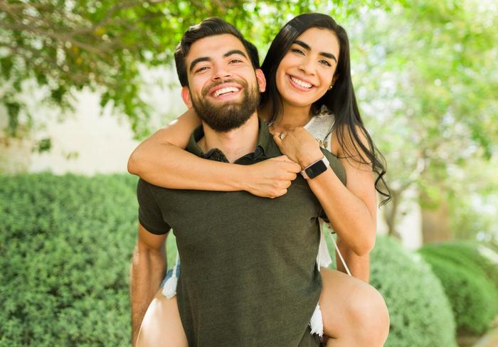a man is carrying a woman on his back .