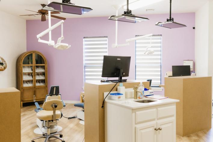 Dental office with lavender walls, multiple chairs, examination lights, and workstations.