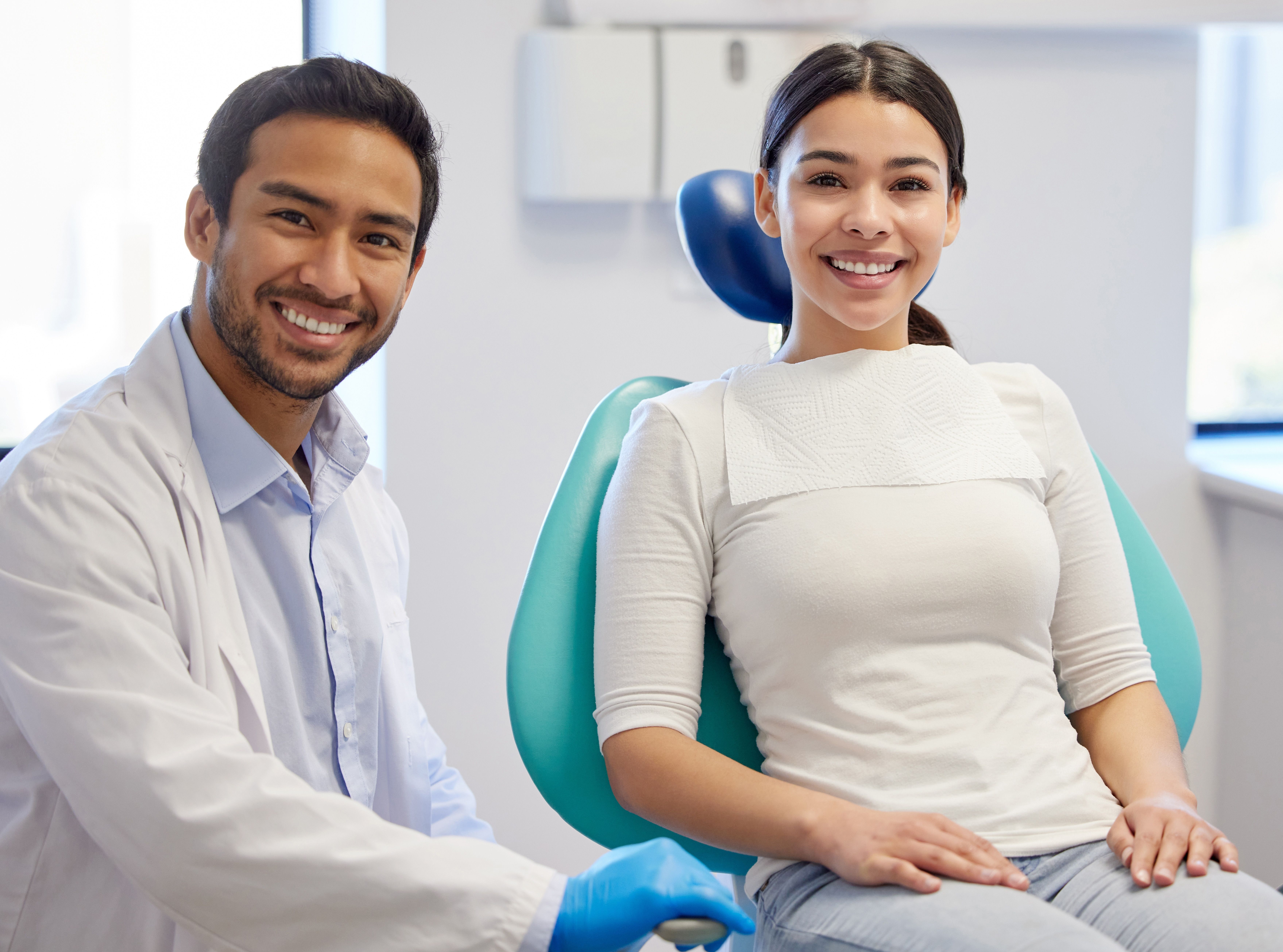 a woman is sitting in a dental chair next to a dentist .