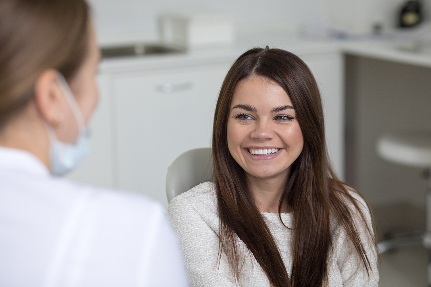 a woman is smiling while talking to a dentist