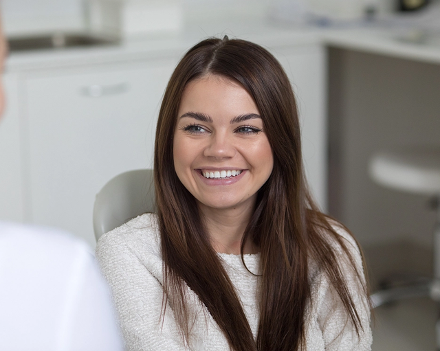 a woman is smiling while talking to a dentist