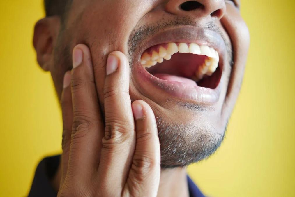 a man is holding his face in pain because he has a toothache .
