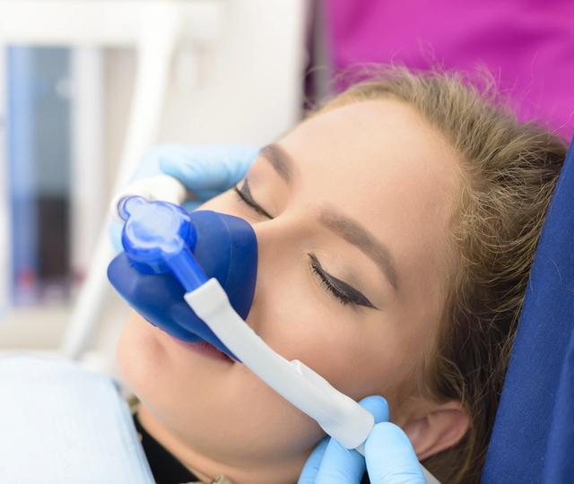 a woman is laying in a dental chair with an oxygen mask on her face .