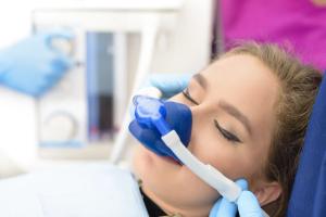 Woman with closed eyes wearing a blue nasal mask for sedation.