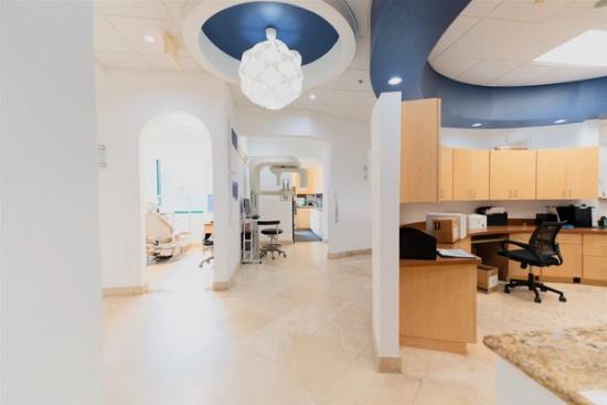 a dental office with a blue ceiling , wooden cabinets , and a desk .