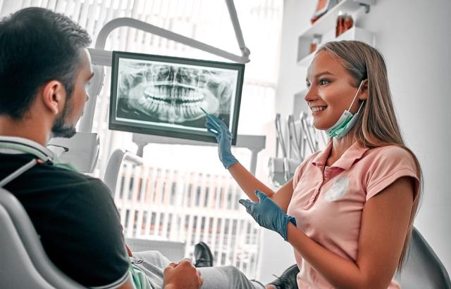 a dentist is showing a patient an x-ray of their teeth .