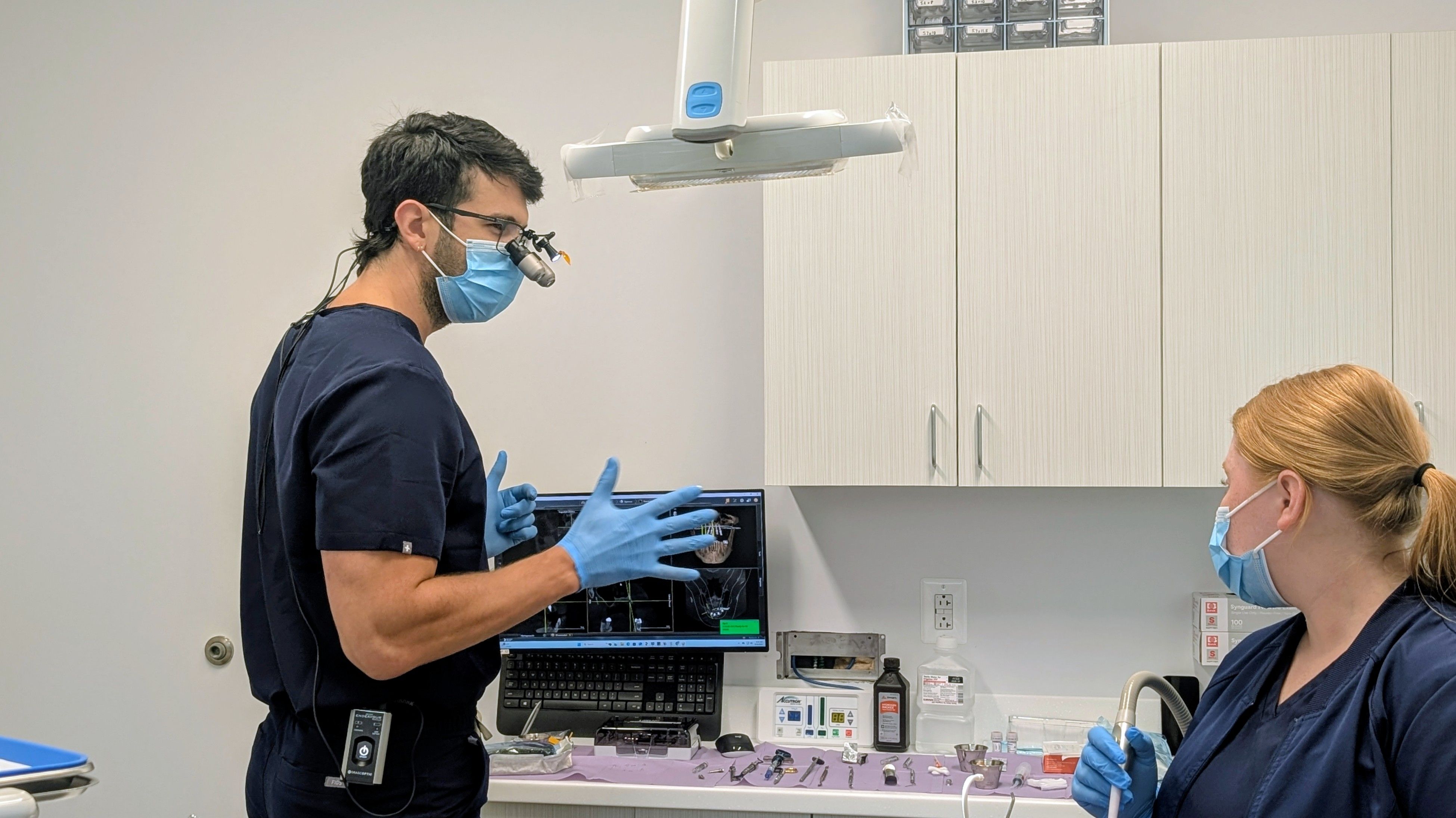 a man and a woman are standing in a dental office looking at a computer screen .