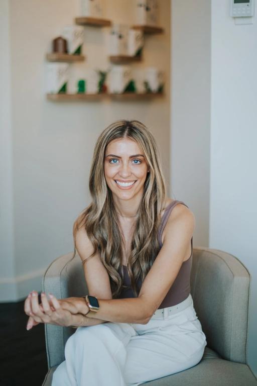 a woman is sitting in a chair with her hands folded and smiling