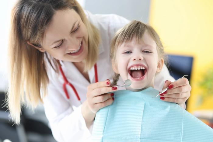 a little girl is having her teeth examined by a dentist .