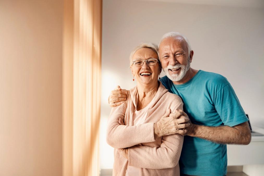 Joyful senior couple with white hair, embracing and laughing.
