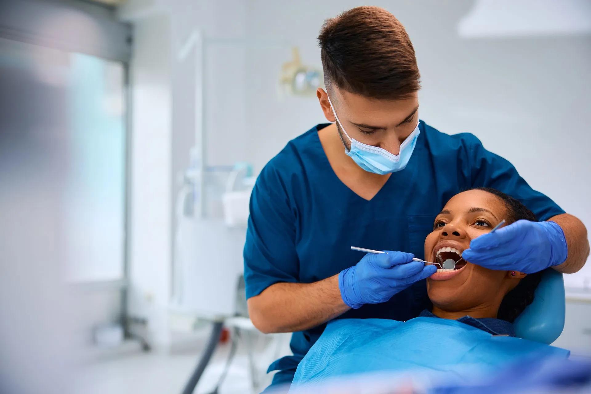 a dentist is examining a woman 's teeth in a dental office .