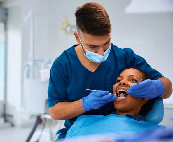 a dentist is examining a woman 's teeth in a dental office .