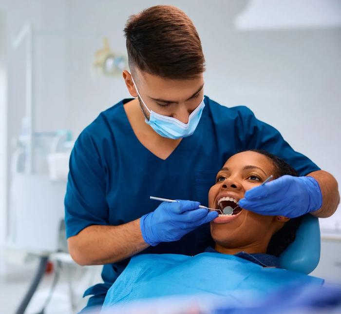 a dentist is examining a woman 's teeth in a dental office .