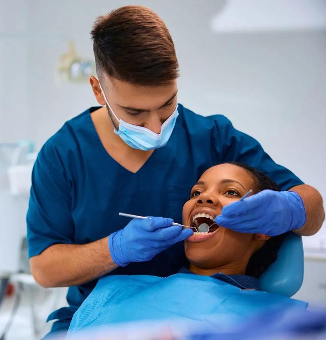 a dentist is examining a woman 's teeth in a dental office .