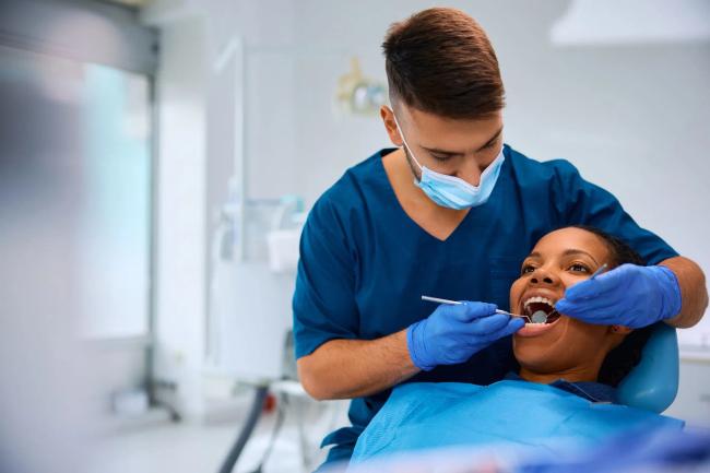 a dentist is examining a woman 's teeth in a dental office .