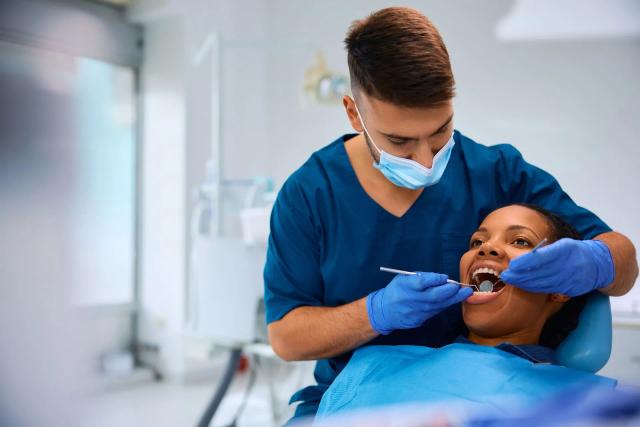 a dentist is examining a woman 's teeth in a dental office .