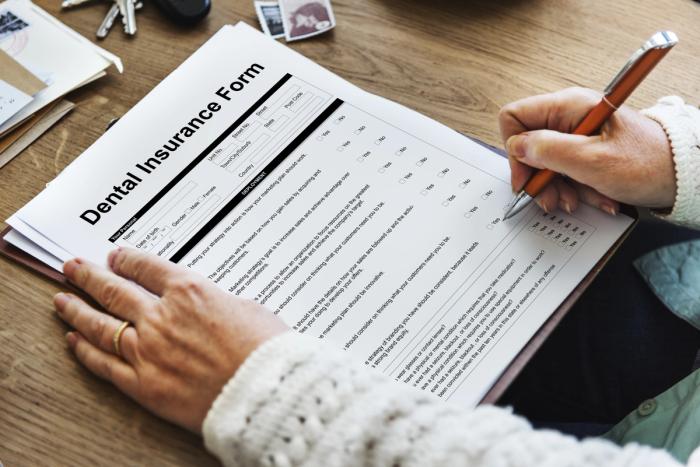 a person is filling out a dental insurance form on a clipboard .