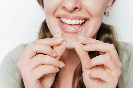 a woman is holding a clear brace in her mouth .