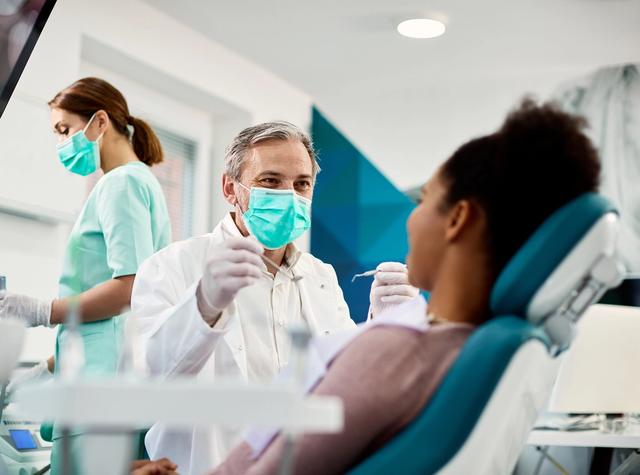 a dentist is examining a patient 's teeth in a dental office .