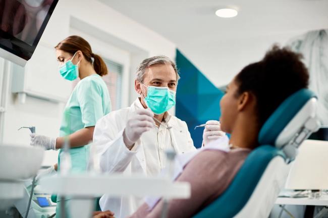 a dentist is examining a patient 's teeth in a dental office .