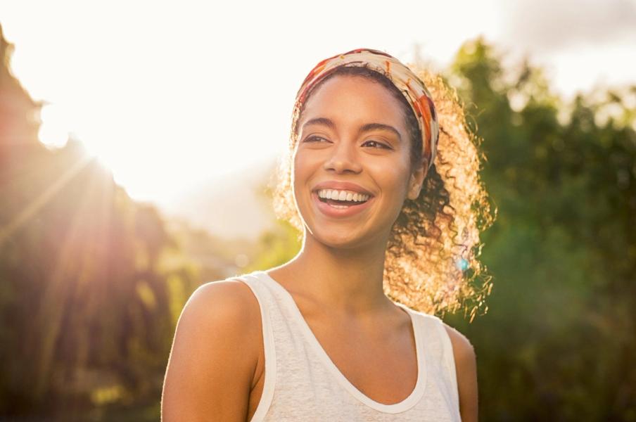 a woman wearing a headband is smiling in the sunlight .