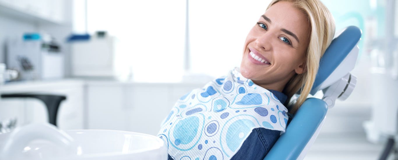 a woman is smiling while sitting in a dental chair