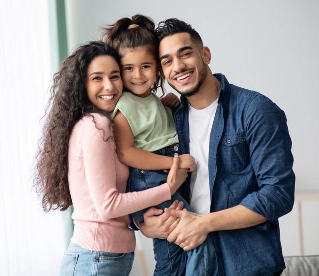 a family is posing for a picture together in a living room .