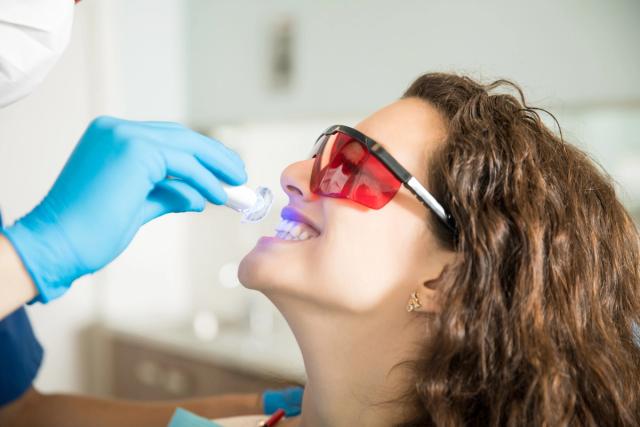 a woman is getting her teeth whitened by a dentist .