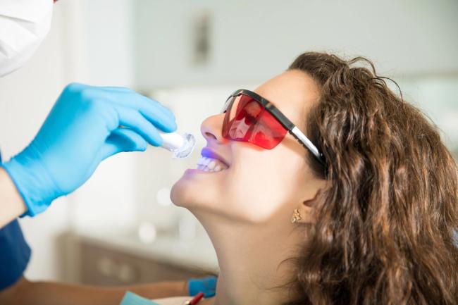 a woman is getting her teeth whitened by a dentist .