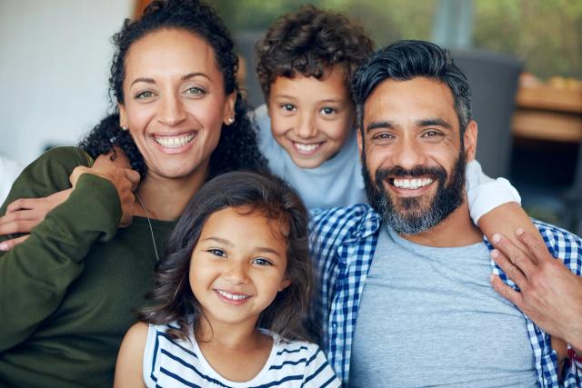 a family is posing for a picture together and smiling for the camera .