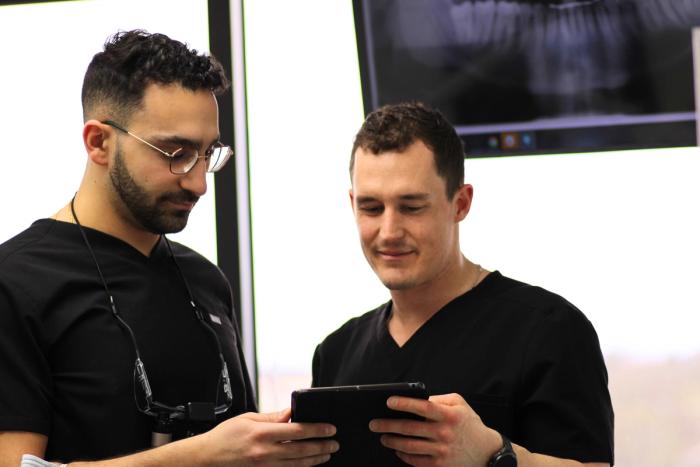 two dentists are looking at an x-ray on a tablet .