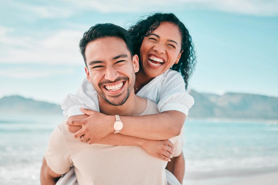 a man is carrying a woman on his back on the beach .