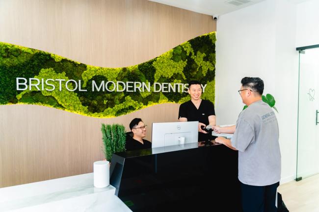 Bristol Modern Dentistry reception with a moss wall, staff assisting a patient.