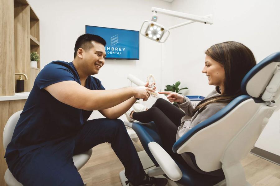 a woman is sitting in a dental chair talking to a dentist .