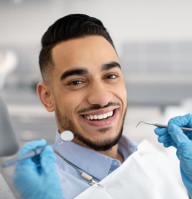 a man is sitting in a dental chair while a dentist examines his teeth .