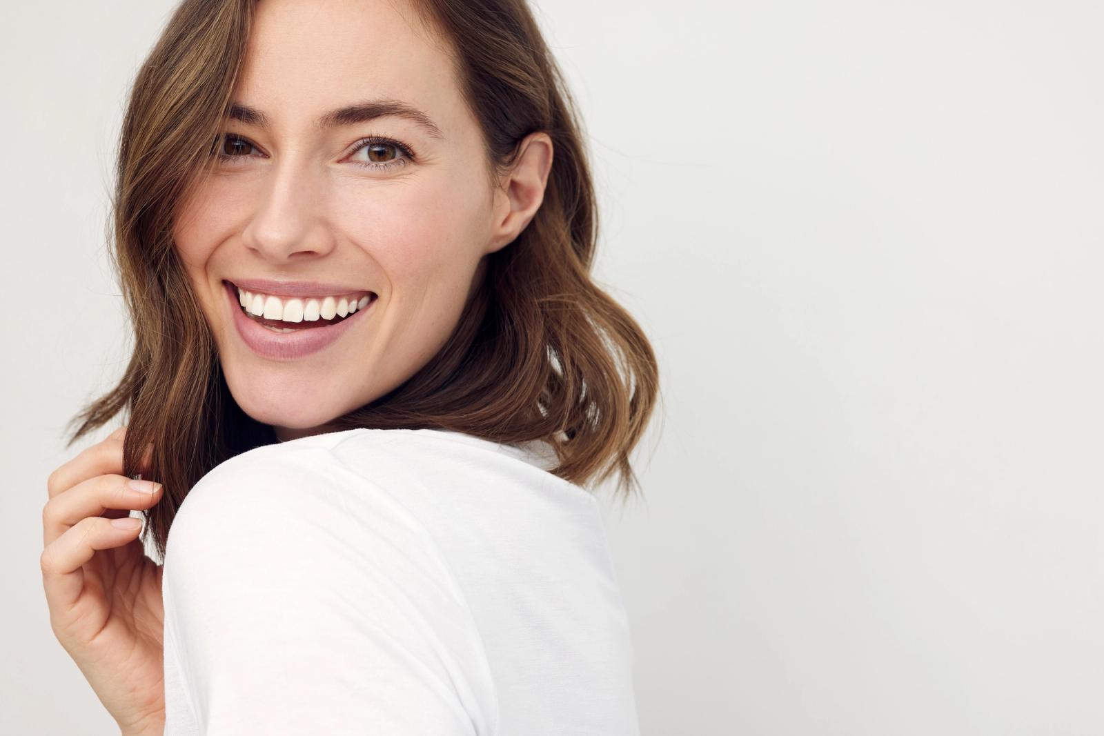 Smiling woman with brown hair looking over her shoulder.