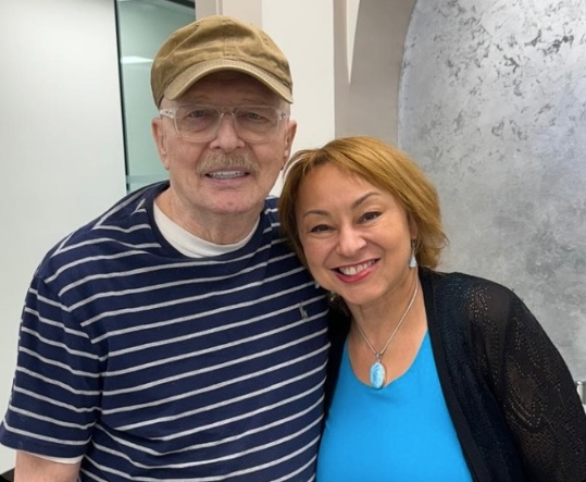 a man and a woman are posing for a picture and the woman is wearing a blue shirt